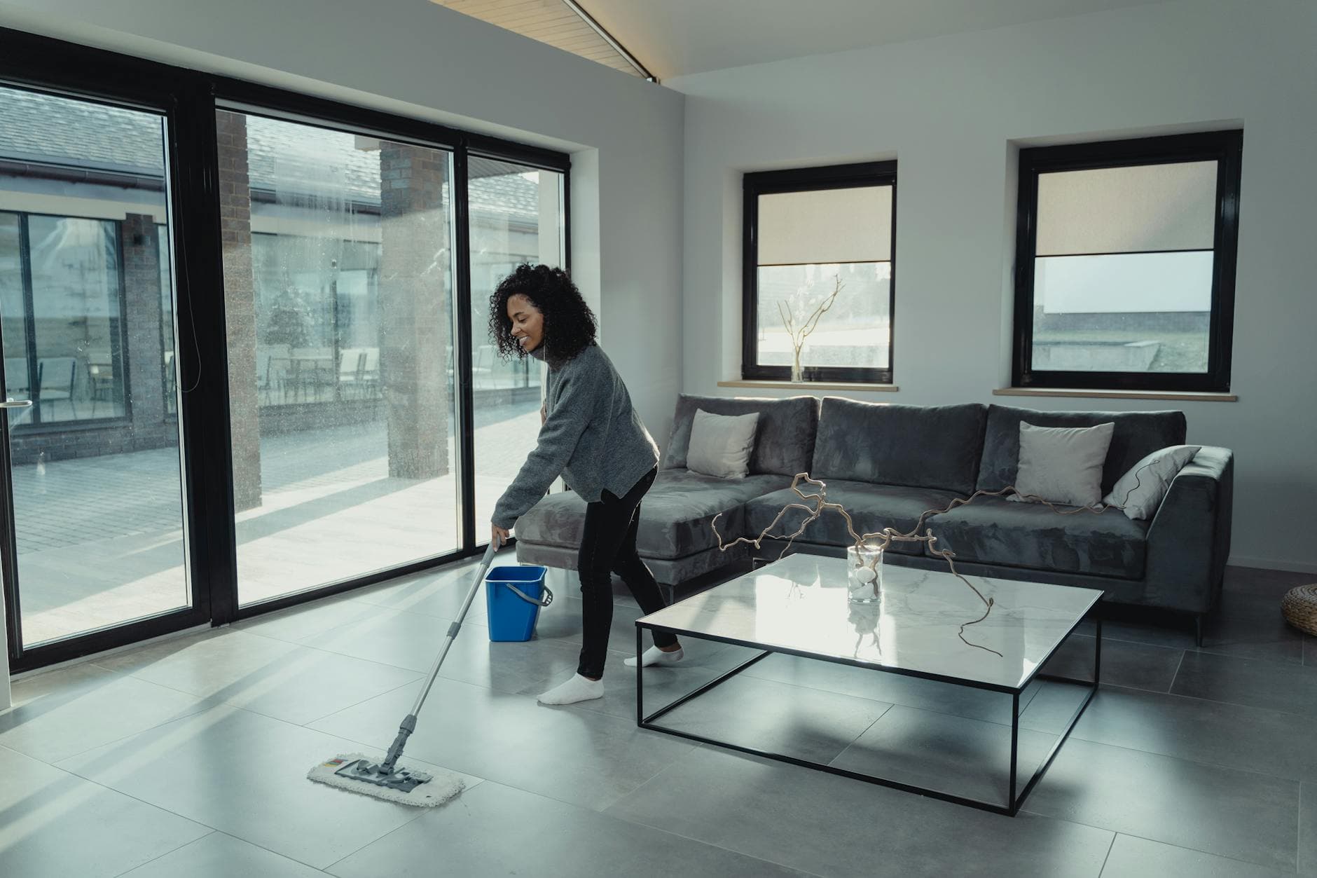 House cleaner mopping a bright, modern New Jersey apartment with large windows — cleaning services in Edison, Central Jersey