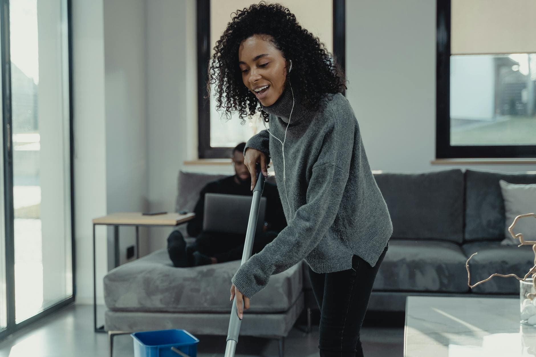 A professional house cleaner mopping the floor of a cozy New Jersey living room — Weekly Maid Service in New Jersey