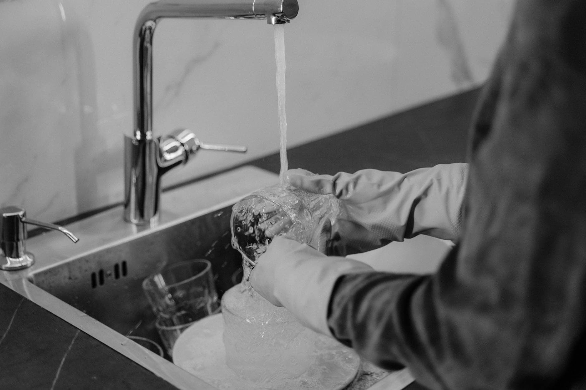 New Jersey kitchen cleaning service washing dishes under running water at the sink — cleaning services in East Brunswick, Central Jersey